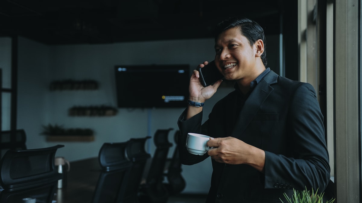 Giám đốc cầm tách cà phê gọi điện thoại trong phòng họp